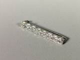 une photo d'une broche en forme de barre de diamant posée sur une surface blanche