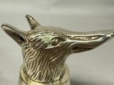 silver bell with a dog head on top of it on a white surface