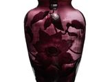 un vase violet orné de fleurs, posé sur une surface blanche