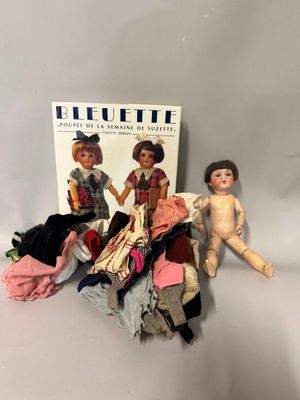 des poupées sont assises à côté d'une boîte de vêtements et d'une poupée
