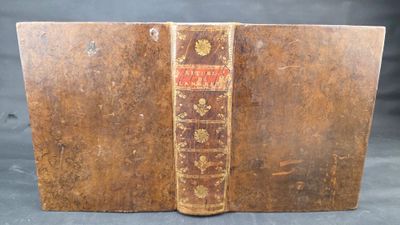 an old book with a brown cover sitting on top of a table