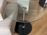 a glass table with a black base in a living room