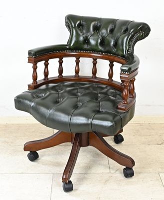 un fauteuil en cuir vert avec un piètement en bois monté sur roulettes
