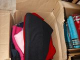 a cardboard box filled with clothes on a tiled floor