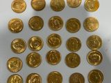 a close up of a pile of gold coins sitting on top of a white surface