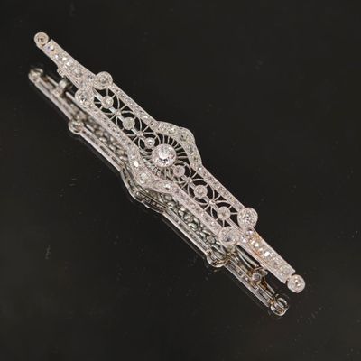un gros plan d'une broche en argent et diamants posée sur une surface noire
