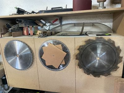 trois lames de scie circulaire posées sur un établi