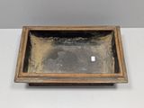 an old wooden tray with a metal lid on a white surface