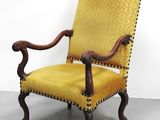 une chaise jaune posée sur un sol en béton, près d'un mur
