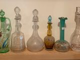 de nombreux vases en verre de toutes sortes posés sur une étagère dans une pièce