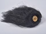 a black hair with a gold button on top of it