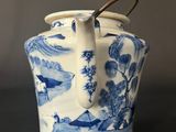 a blue and white vase with a handle on a table