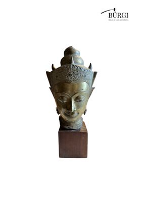 bronze head of a buddha statue on a wooden base