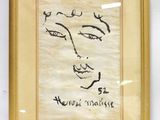 tableau représentant le visage d'une femme, dans un cadre doré, accroché à un mur blanc