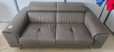 grey leather sofa in a room with clothes hanging on the wall