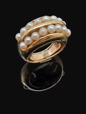 un gros plan d'une bague ornée de perles sur un fond noir