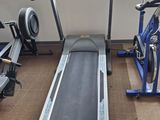 an image of a gym room with a treadmill and stationary bikes