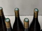 bottles of wine are lined up in a glass holder on a counter