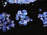 blue glass beads are scattered on a black surface with a black background