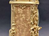 a gold clock with a statue on top of it