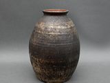 un vase noir et marron posé sur une surface grise