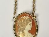 a close up of a necklace with a woman ' s face on it