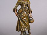 statue en bronze représentant une femme tenant un panier, posée sur un socle en bois