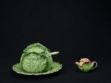 une figurine représentant un chou posé sur une assiette à côté d'une théière