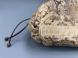 snake skin purse on a blue surface with a brown cord