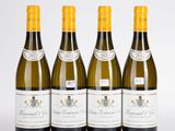 quatre bouteilles de vin sont alignées sur une surface blanche