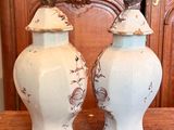 two white vases sitting on a table with a wooden door in the background
