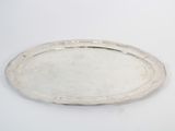 an oval silver tray on a white surface with a silver handle