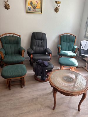 plusieurs chaises et une table dans un salon où est accroché un tableau au mur