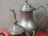 une théière en argent et une théière en argent posées sur une table rouge