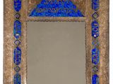 un miroir en verre bleu avec un cadre doré et un motif décoratif