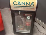 a soda dispenser sitting on the floor next to a red chair