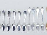 several forks and spoons are lined up on a white surface