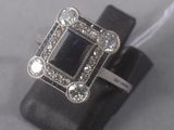 an image of a ring with a black stone surrounded by white diamonds