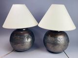 une paire de lampes en forme de vases en argent, surmontées d'abat-jour blancs