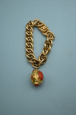 an image of a gold chain bracelet with a red bead on it