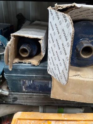 une boîte remplie de rouleaux de ruban adhésif bleu, à côté d'autres rouleaux de ruban adhésif bleu