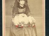 une vieille photo d'une femme assise sur une chaise, tenant un bébé dans ses bras