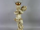 un bougeoir blanc surmonté d'une statuette