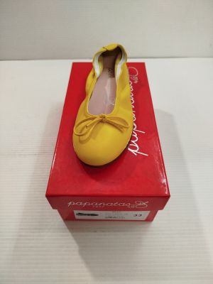 des chaussons de danse jaunes ornés d'un nœud, posés sur une boîte rouge