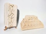 two pieces of carved stone with carvings on them on a white surface