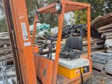 a forklift that is parked in front of a pile of wood