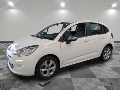 the small white car is parked on a checkered tile floor