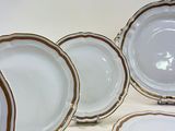 several white and gold plates are arranged on a white surface