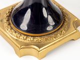 a black and gold vase sitting on top of a gold stand