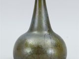 a green glass bottle that is sitting on a table